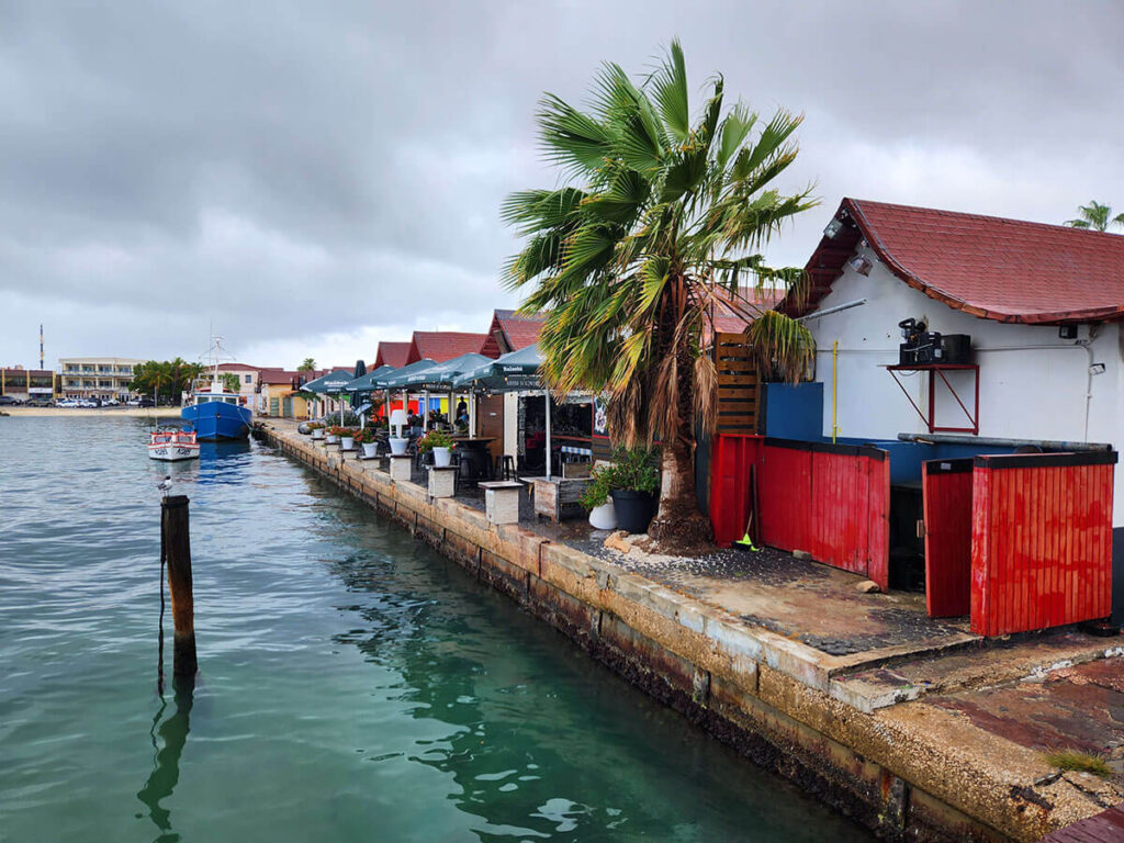 red fence and a small hut at a pier on a cloudy day in Aruba
