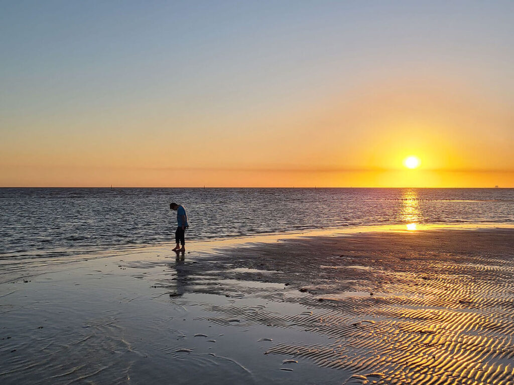 young boy wading in shallow surf at sunset in Mississippi